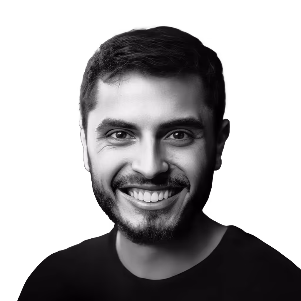 Smiling young man with a beard against a black background.