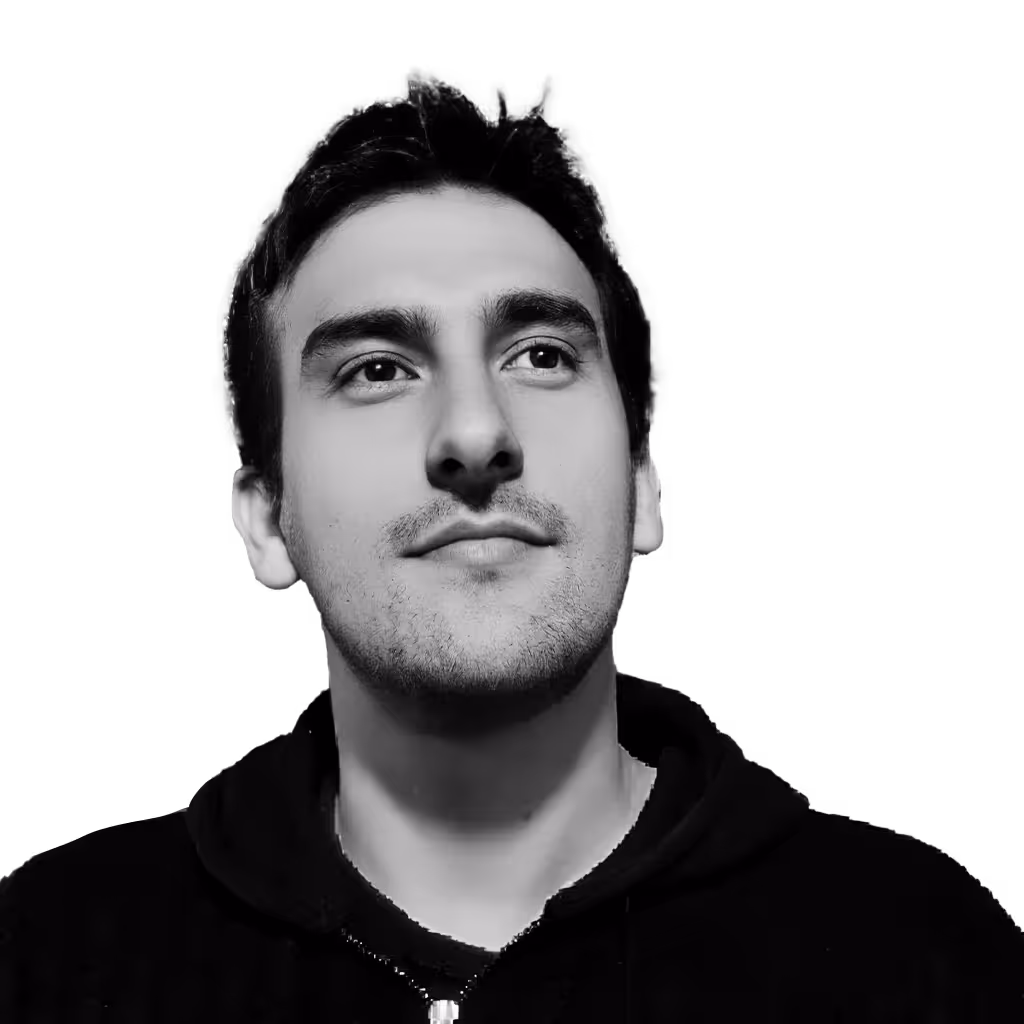 Black and white portrait of a young man with short dark hair looking slightly upward, wearing a dark hoodie.