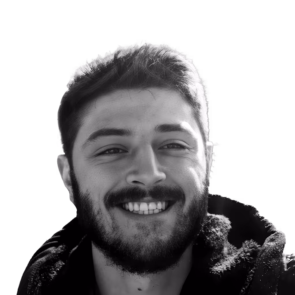 Smiling young man with short hair and a beard wearing a dark jacket with a textured collar.