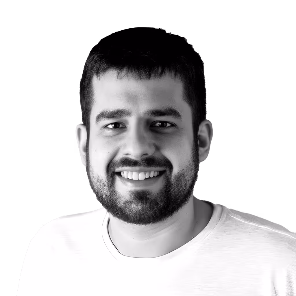 Smiling man with short dark hair and a beard wearing a white shirt.