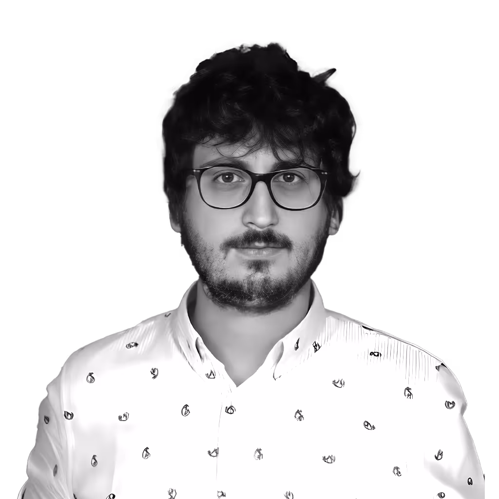 Young man with curly hair and beard wearing glasses and a white shirt with small black lobster prints.