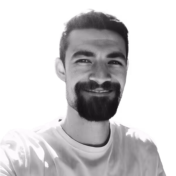 Smiling man with short dark hair, a beard, and a mustache wearing a white T-shirt.