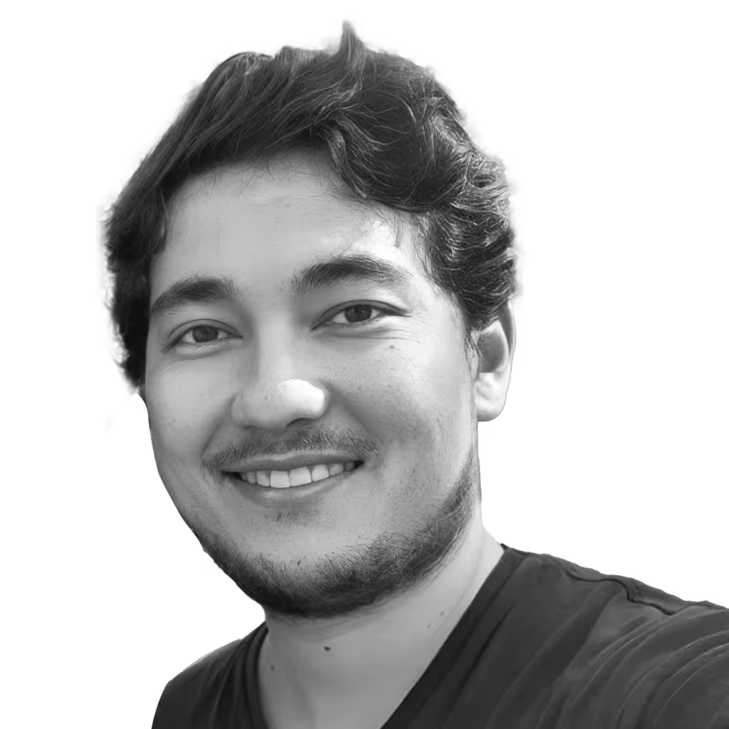 Smiling young man with wavy dark hair and light facial hair wearing a dark shirt.