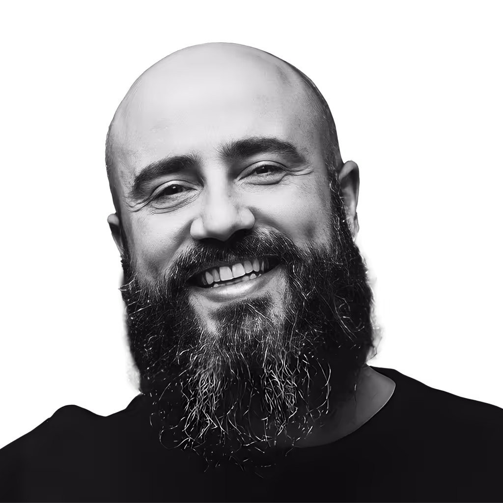 Smiling bald man with a full dark beard and mustache wearing a black shirt.