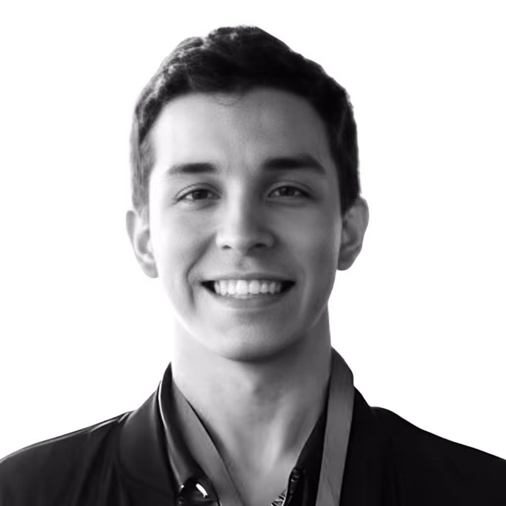 Smiling young man with short dark hair wearing a dark jacket and shirt.