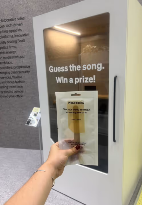 Persy Booth mit einem Werbeschild, das Besucher zur Teilnahme an einem Wettbewerb ermutigt