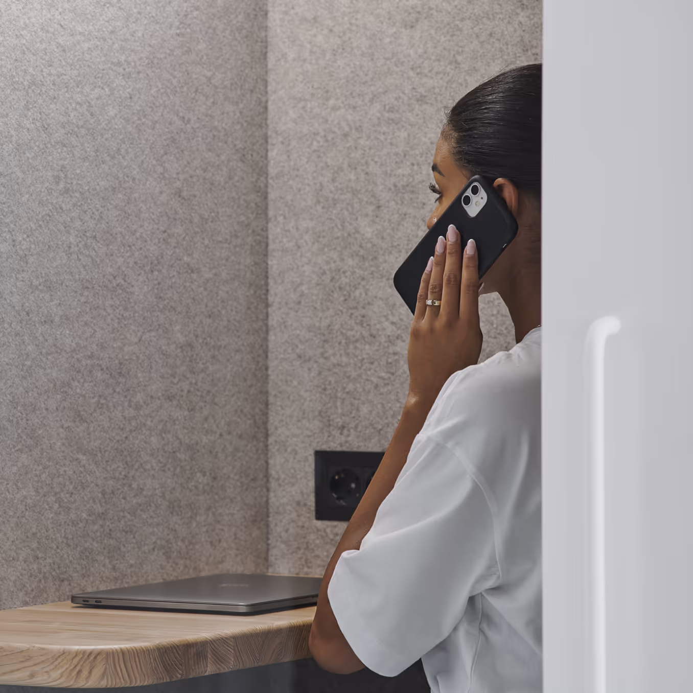 Personne passant un appel téléphonique privé à l'intérieur d'une capsule insonorisée Persy Booth avec panneaux acoustiques