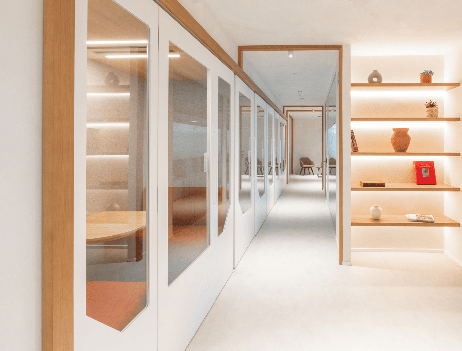 Row of stylish office meeting pods with glass doors and acoustic seating in contemporary workspace