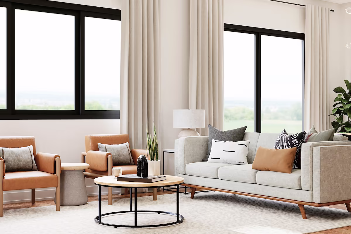 Modern living room with beige sofa, two tan armchairs, round coffee table, large windows and neutral decor.