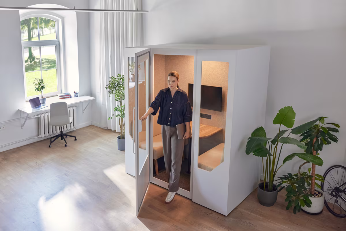 Person entering an acoustic office phone booth designed for private calls in an open workspace