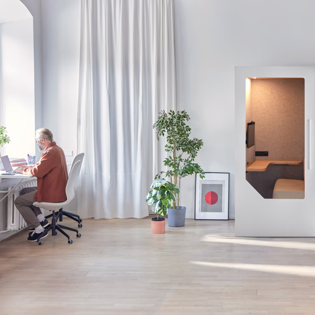 Person working at a desk near an office pod in an open workspace