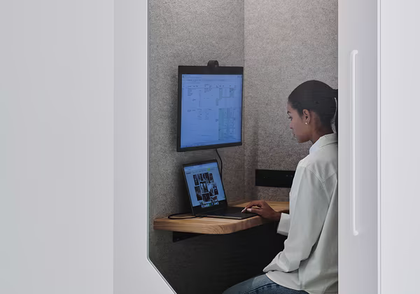 Employee using an office pod for focused work and private video calls