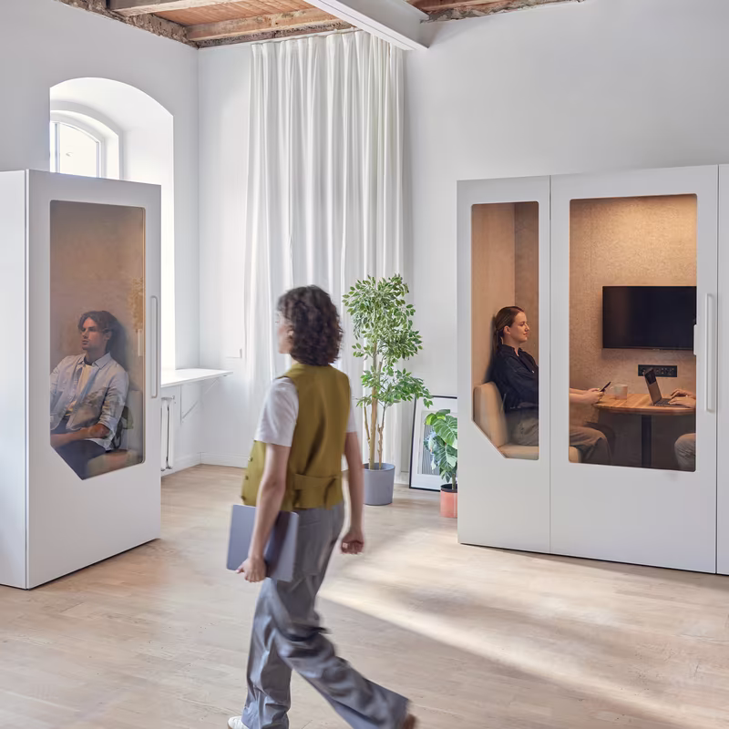 Student walking between soundproof study booths in a university learning space.