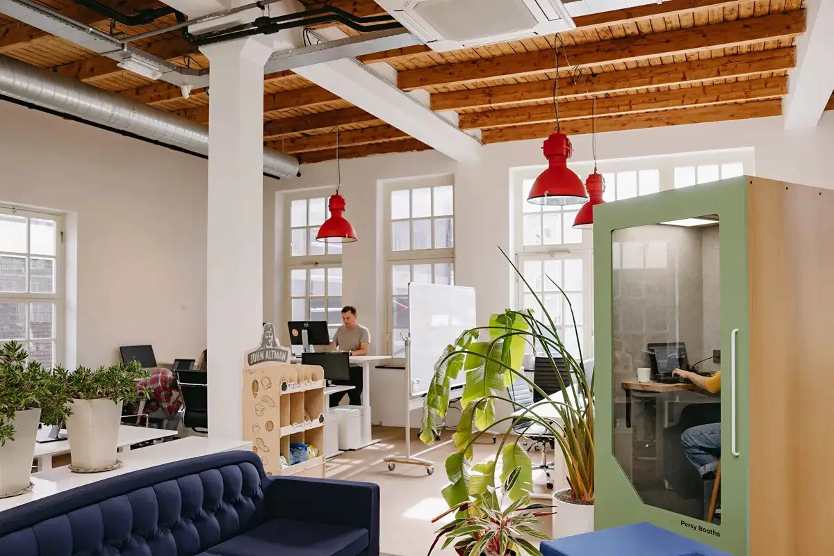 Modern open office featuring a Persy Booths soundproof pod that enhances privacy and focus while maintaining an open, collaborative environment.