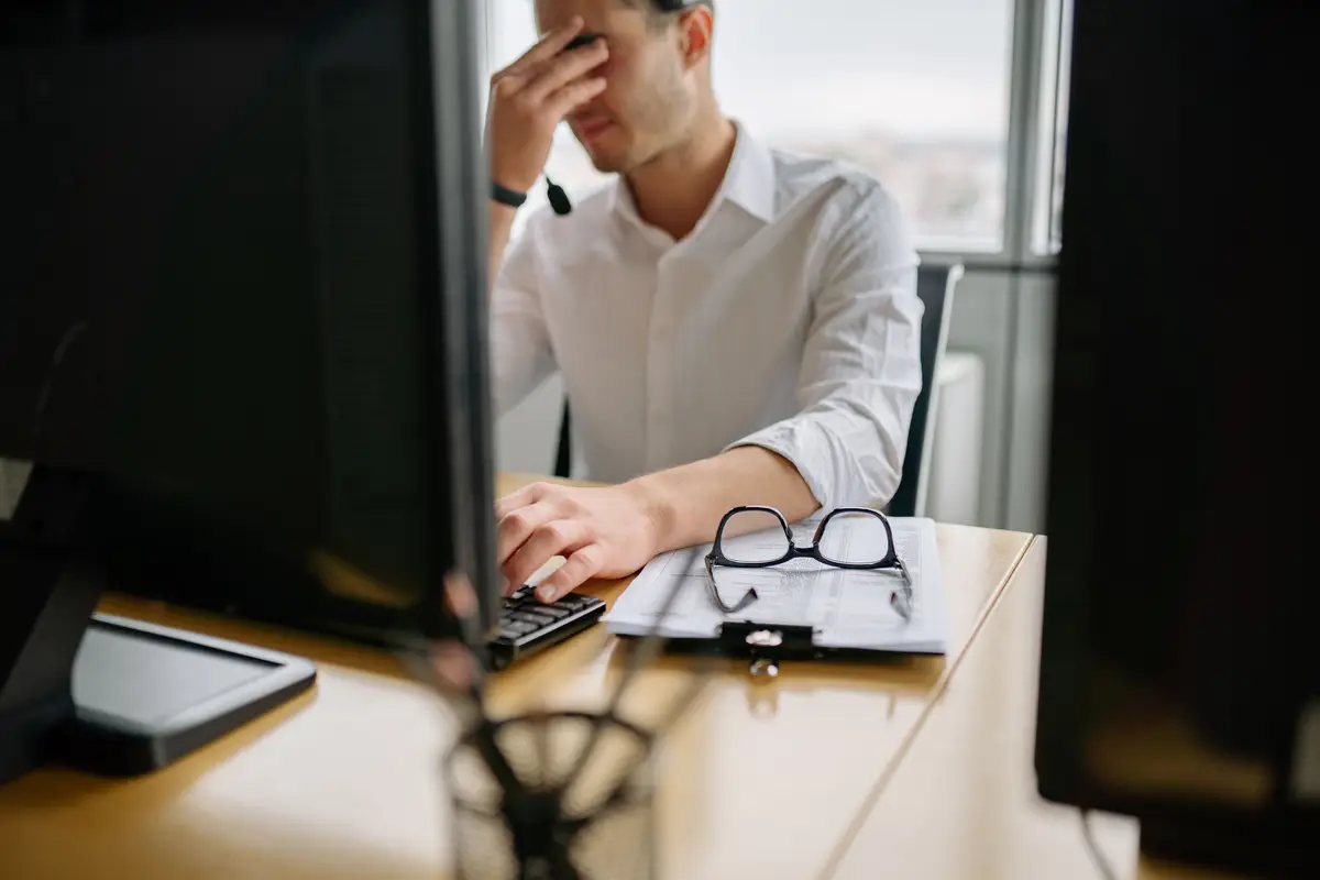 Stressed employee holding head in hands at office desk