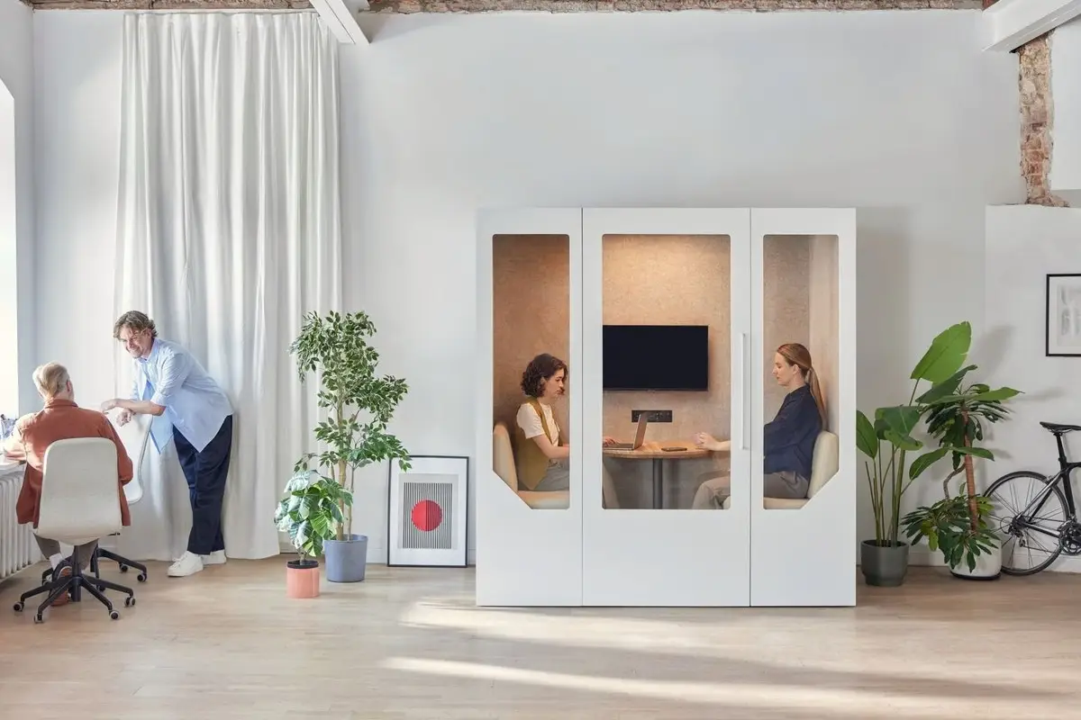 Two employees in a Persy meeting pod in an open plan office