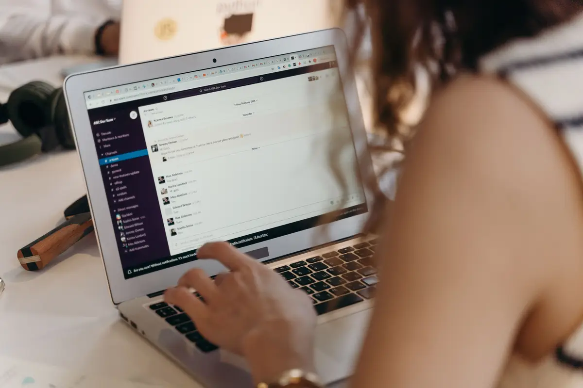 Employee scrolling through instant messages on a laptop in the workplace