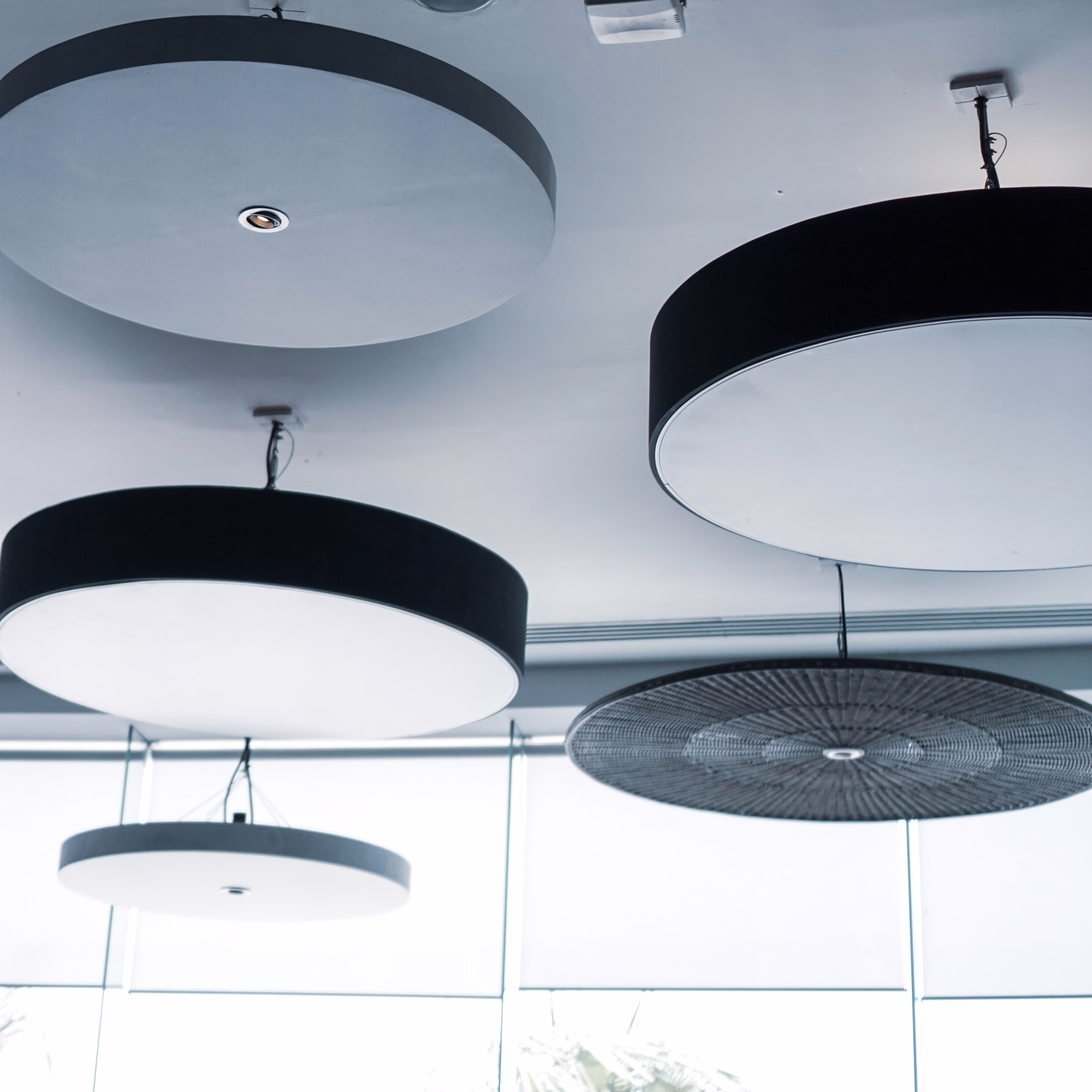Acoustic ceiling panels and light discs suspended in an open-plan office
