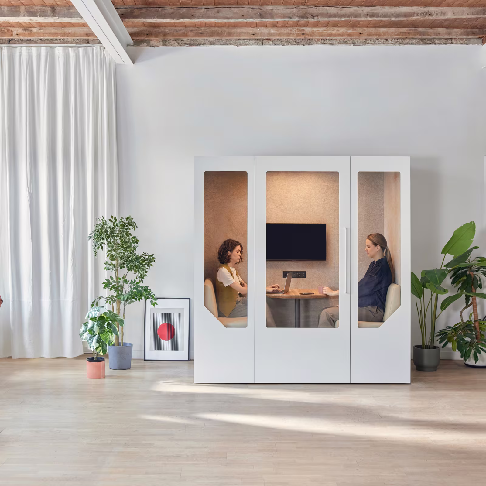 Team having a meeting inside a soundproof office pod in an open workspace