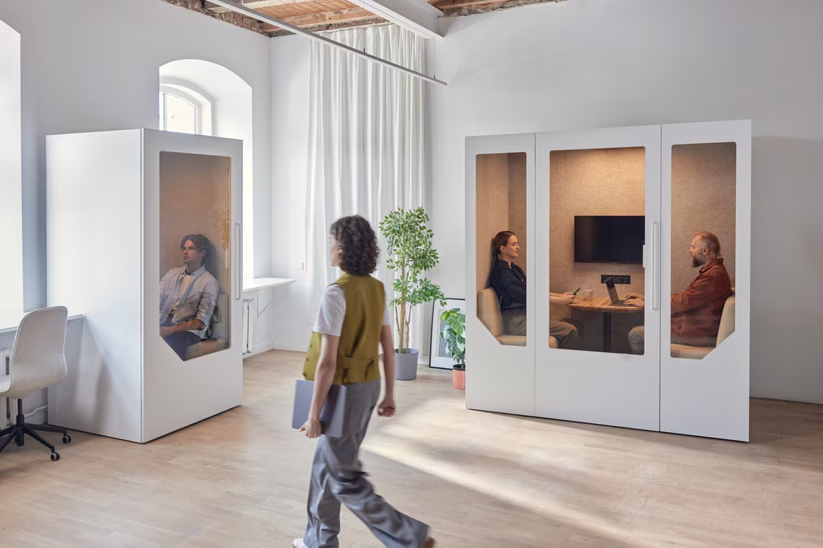Solo phone booth and two-person meeting pod in use in a bright office