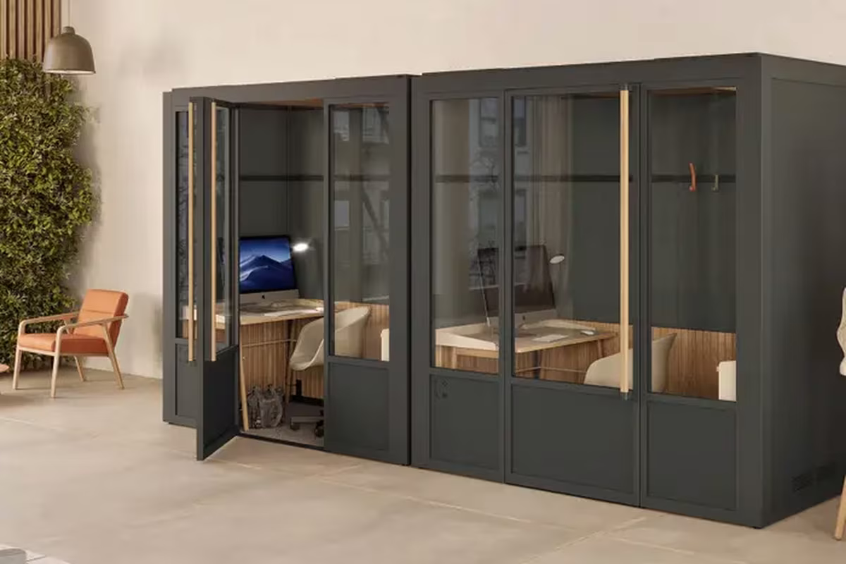 Dark green office pods with wood interiors and desk workstations
