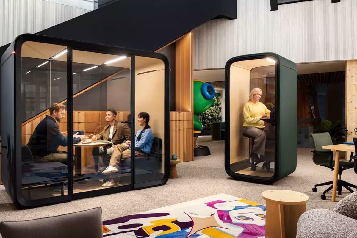Team meeting in a Framery pod next to a solo phone booth in an open office