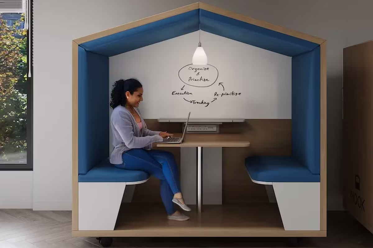 Woman working on a laptop inside a semi-open Nook work pod