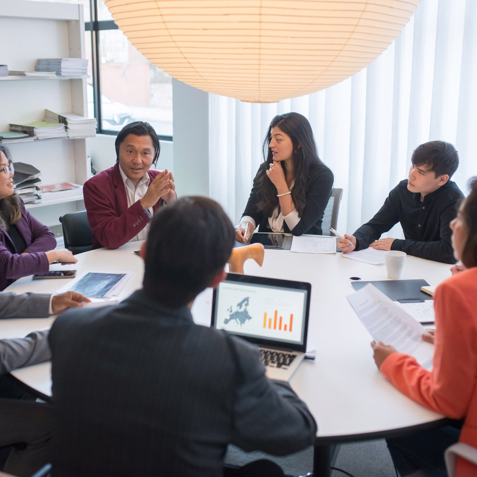 A diverse team of professionals having a collaborative meeting around a conference table in a bright modern office.