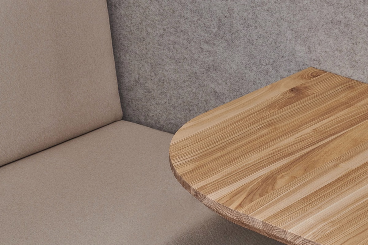 Beige upholstered seating and a natural wood table inside a grey felt-lined acoustic office booth.