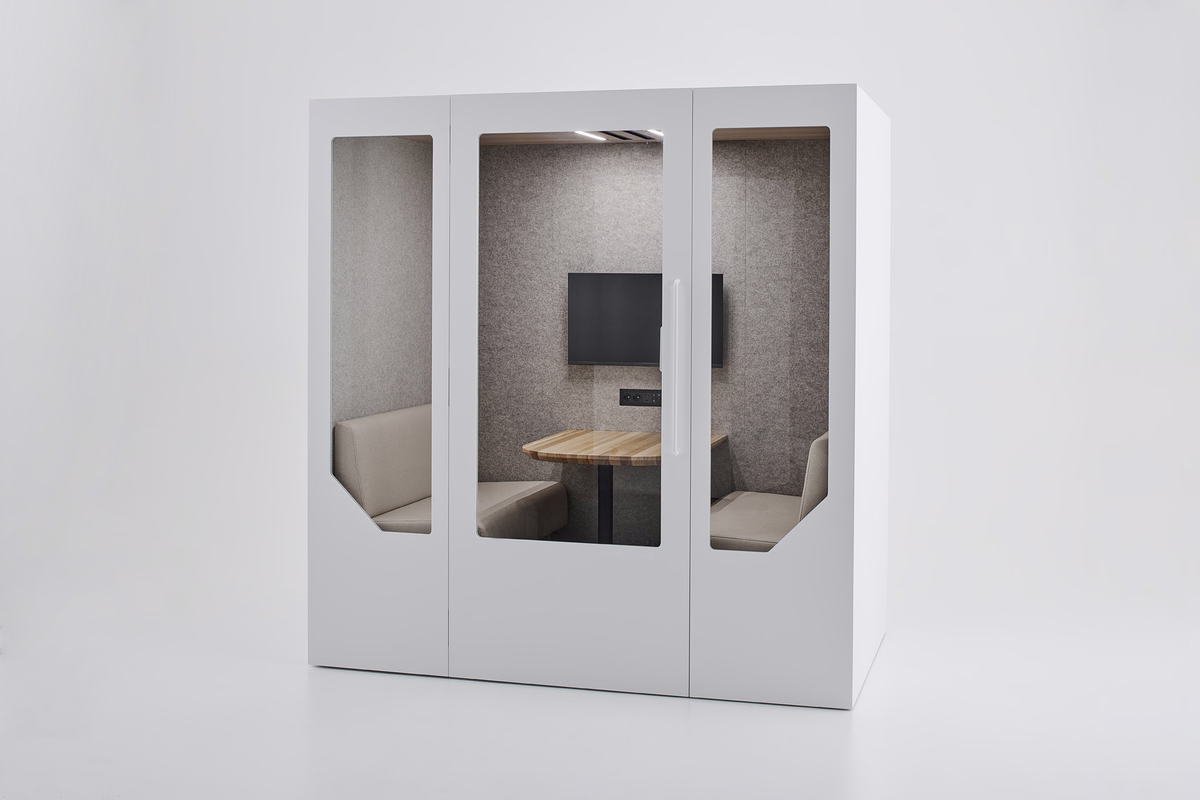 White Persy Four acoustic office booth with glass doors, upholstered seating, a wooden table, and a wall-mounted monitor in a softly lit interior.