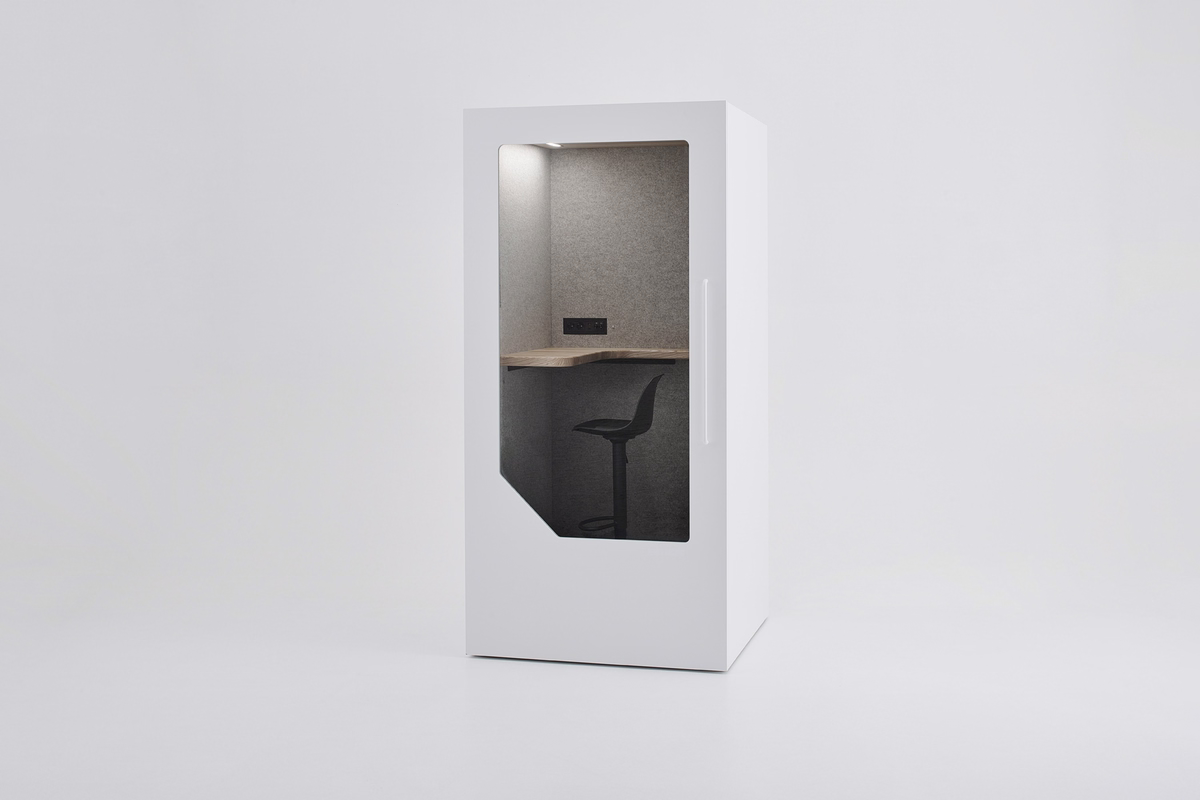 White Persy One acoustic phone booth with a wooden standing desk, black adjustable stool, power outlets, and grey acoustic interior.
