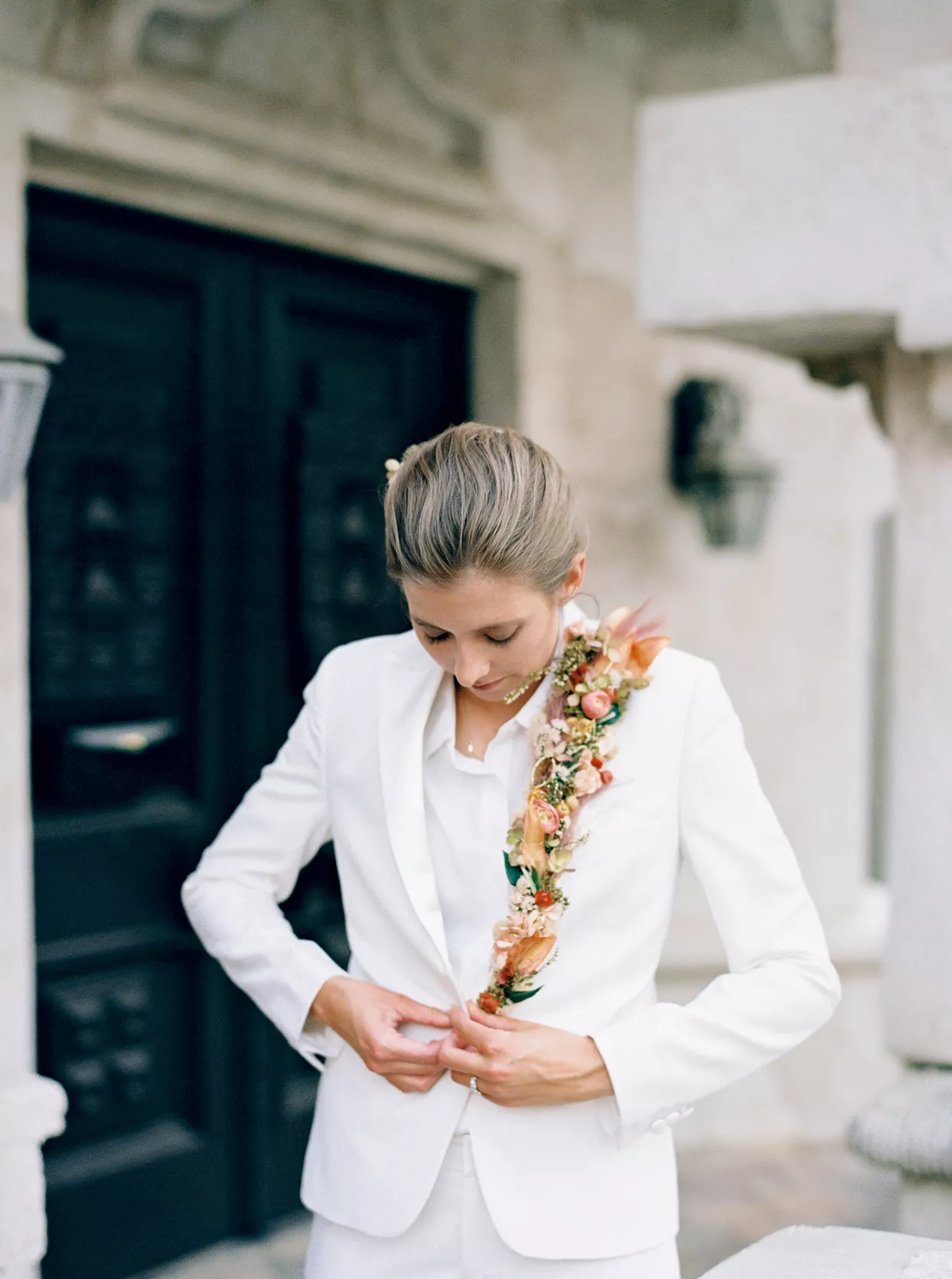 bride buttoning white wedding suit