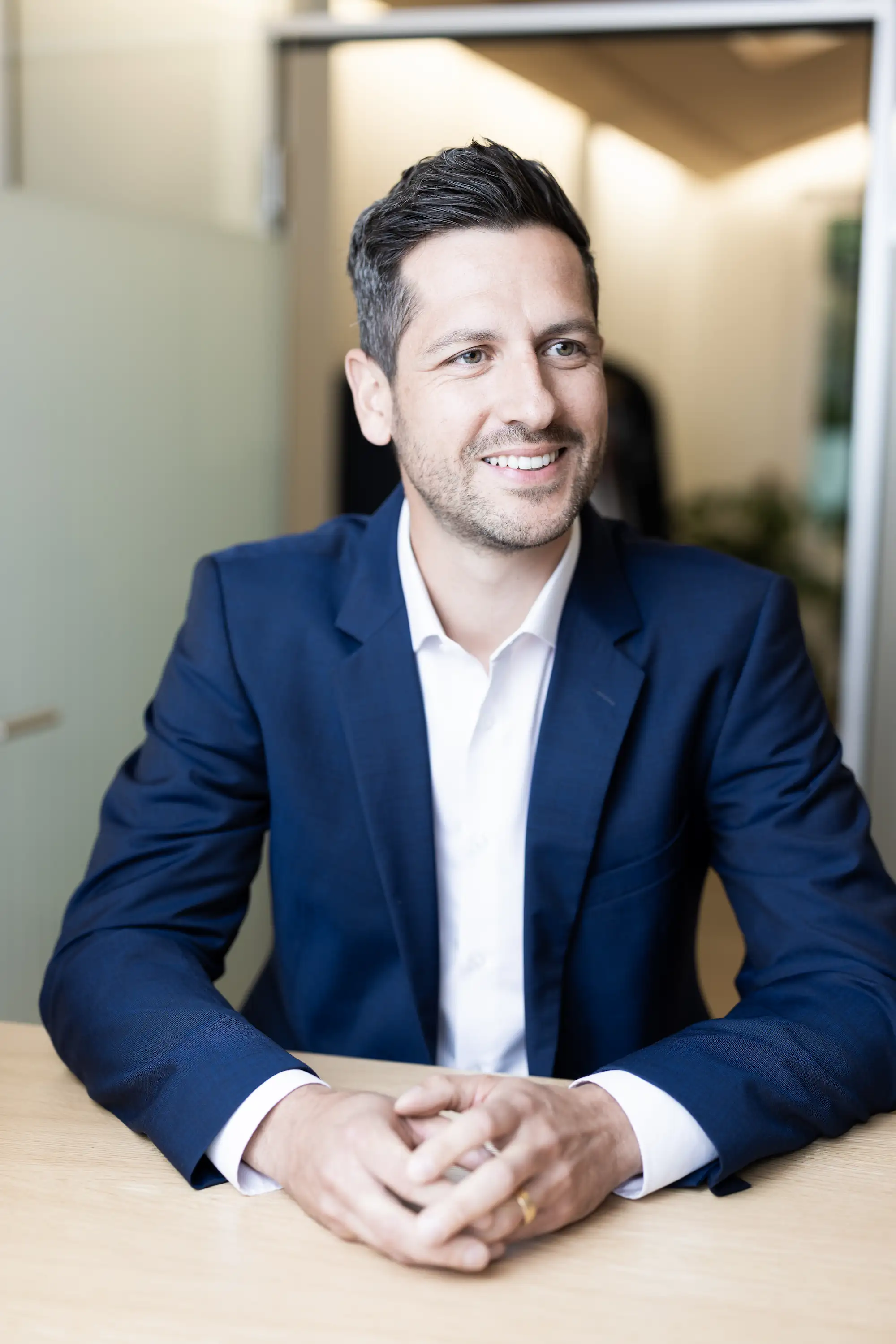 Yves Süess, Gründungspartner, im dunkelblauen Anzug, der an einem Tisch sitzt und einem Gegenüber zuhört.