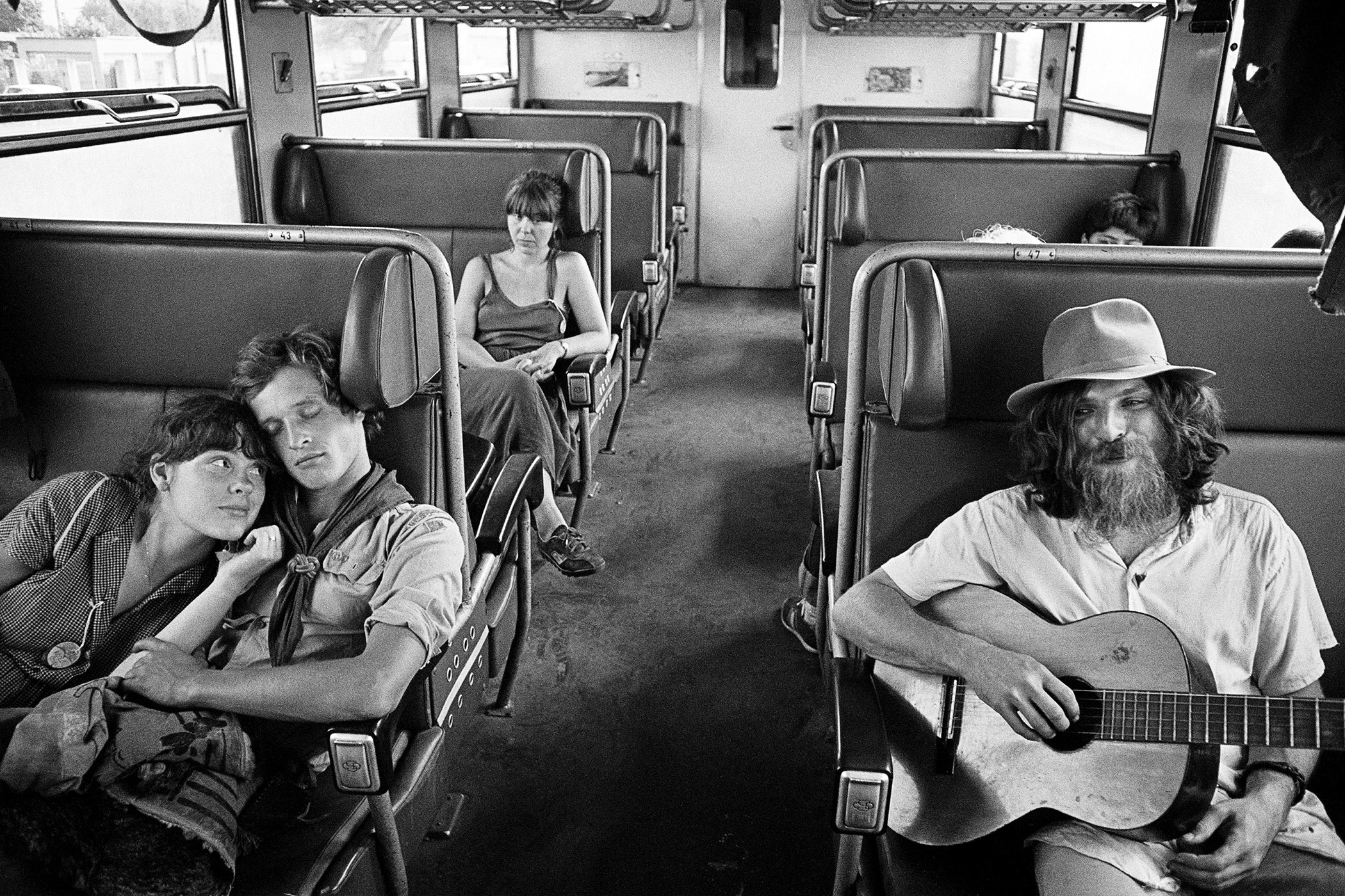 Skupina trampů jedoucích ve vlaku během letního dne. Na jedné straně zamilovaný pár, na druhé zarostlý mladík s kytarou