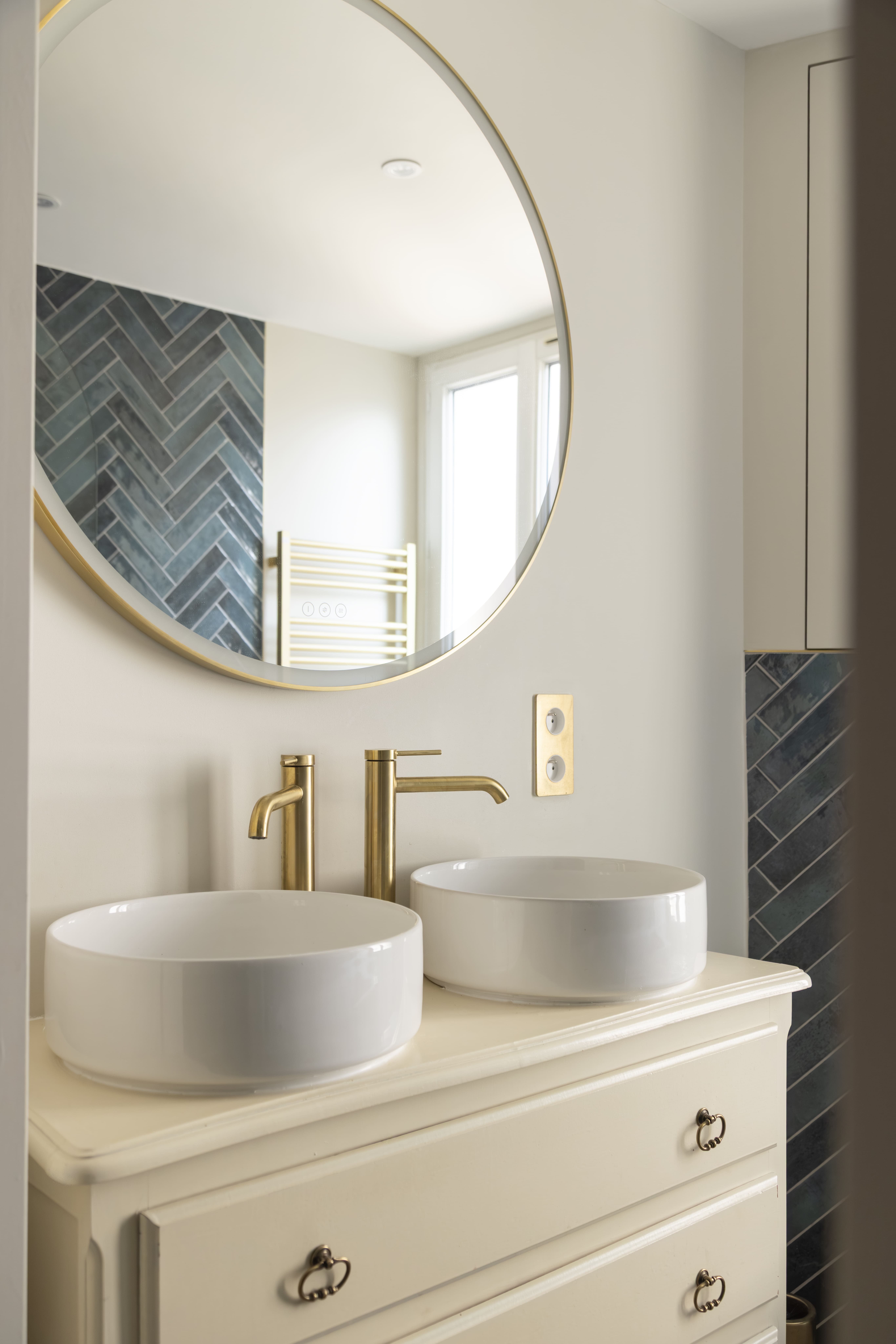 Détail de la vasque ronde et robinetterie dorée dans une salle de bain rénovée