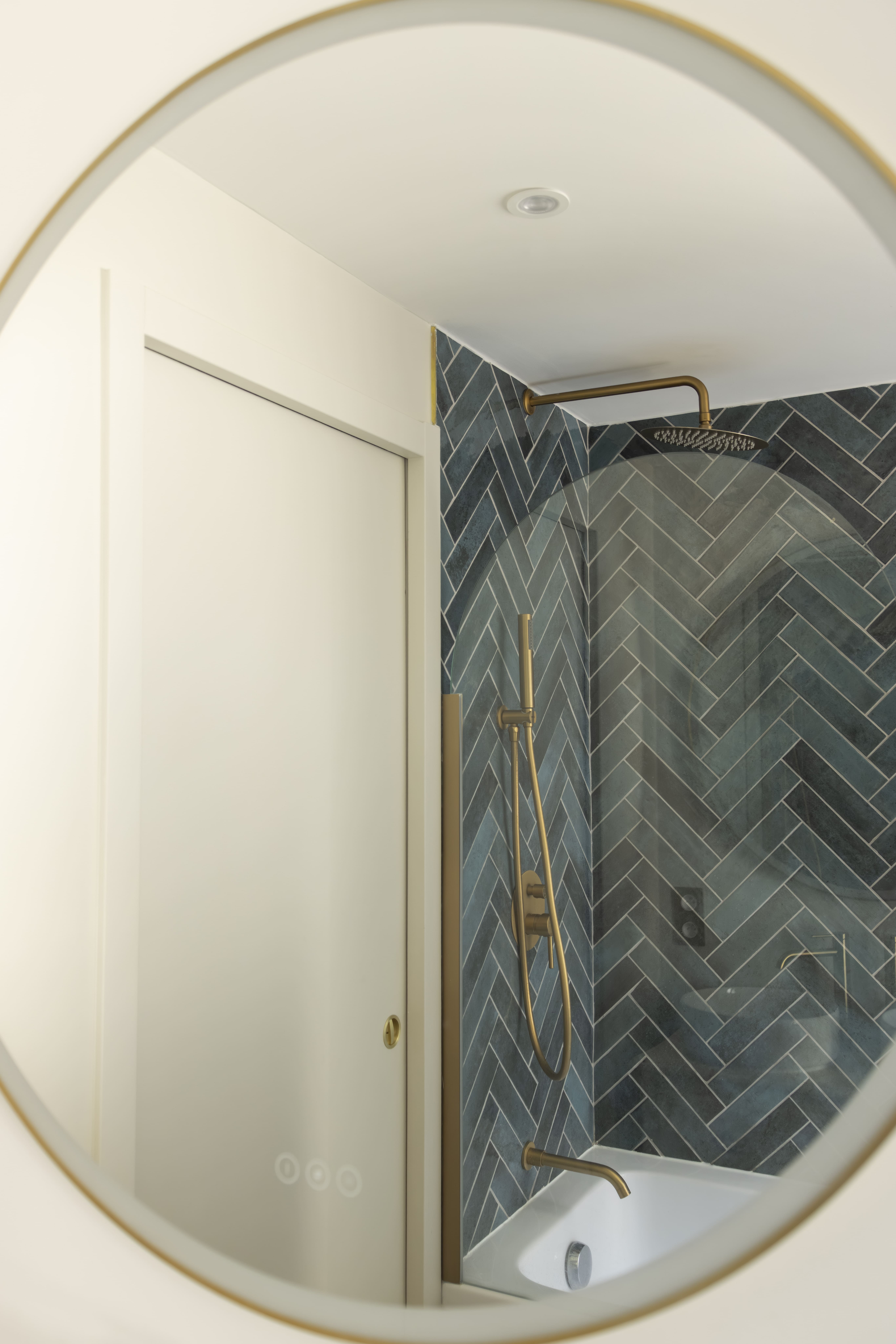 Salle de bain rénovée à Paris avec carrelage bleu en chevron et douche moderne