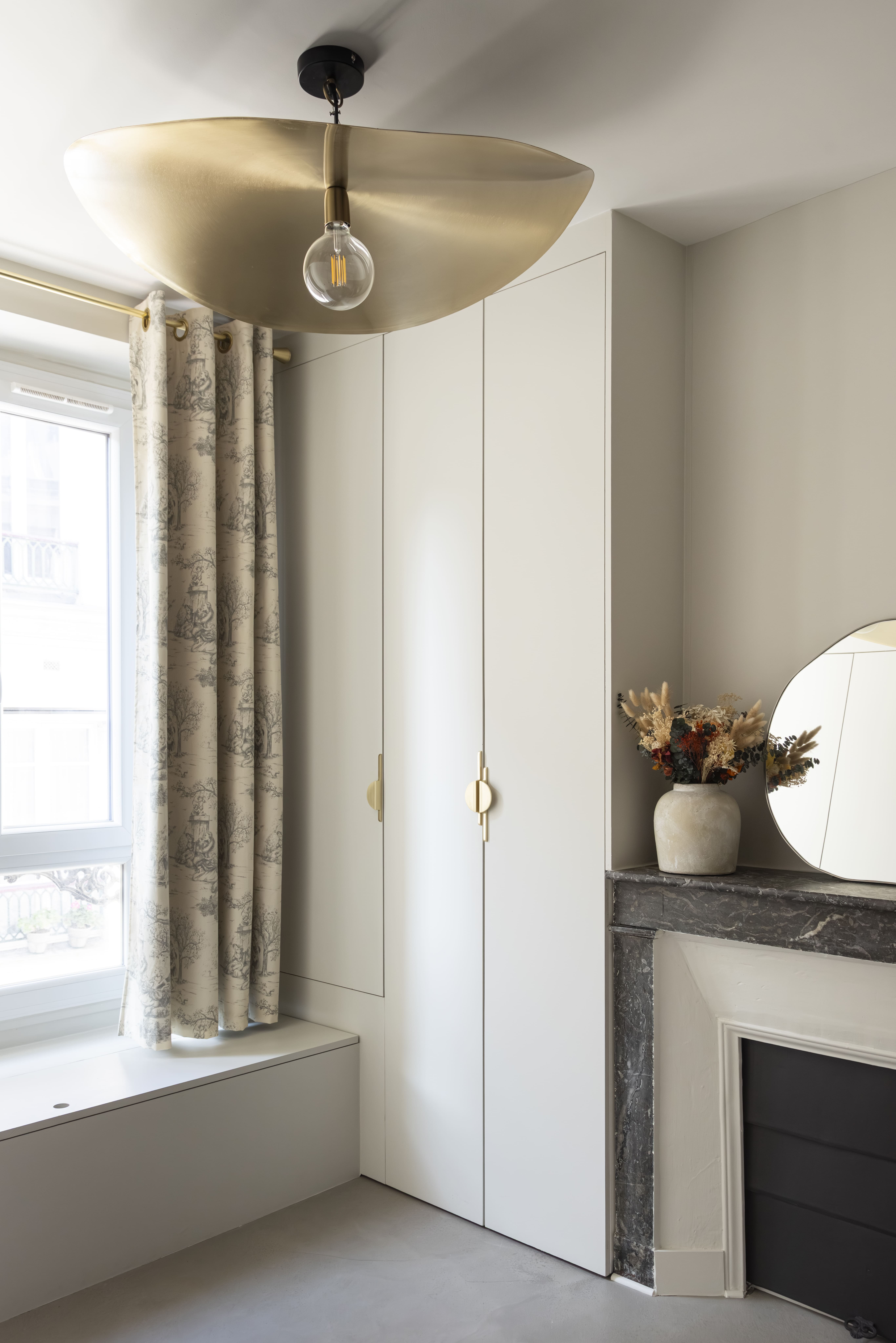 Vue d’ensemble d’une chambre lumineuse avec cheminée, placards sur mesure et rideaux à motifs