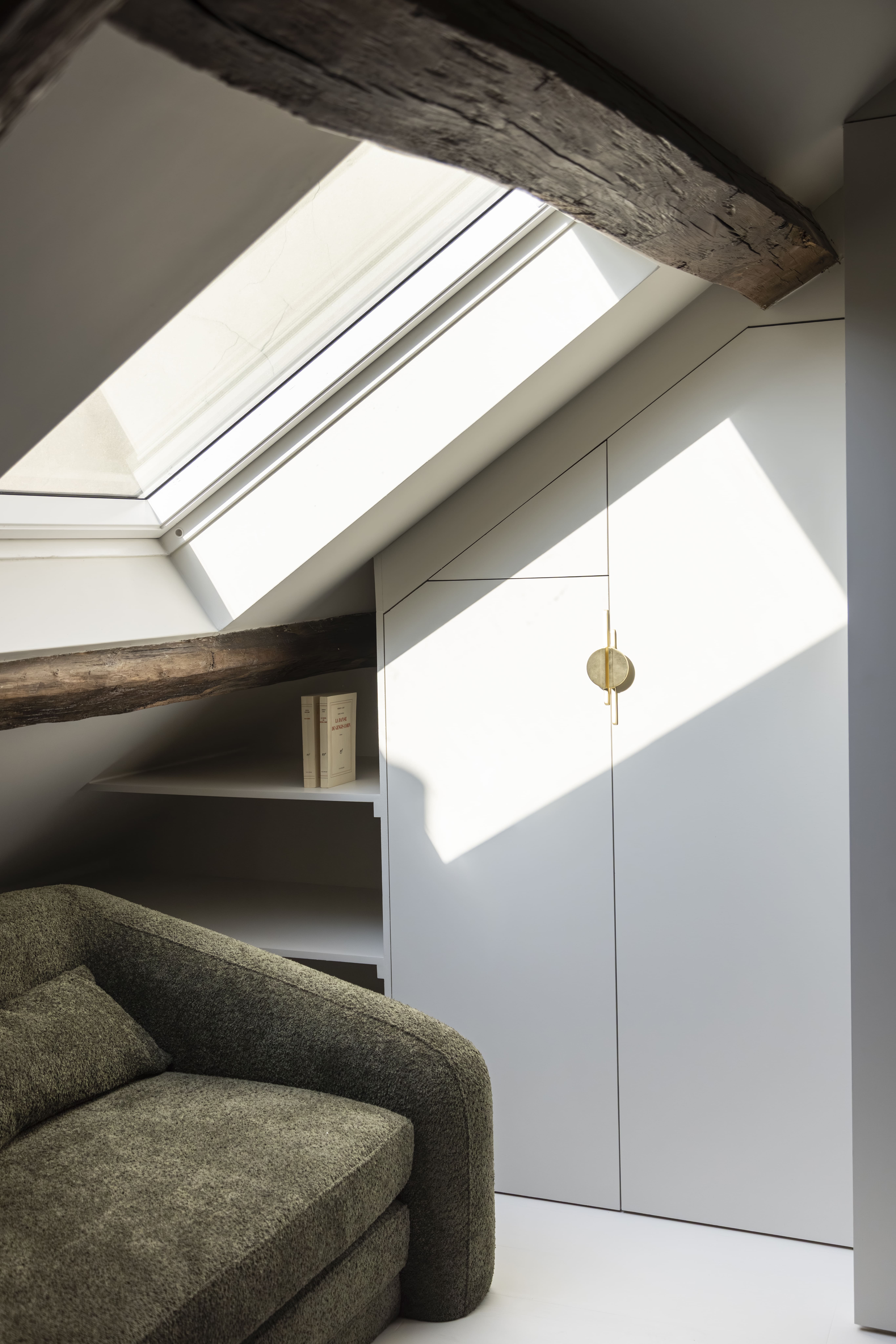 Coin lecture sous les combles avec fauteuil vert et lumière naturelle – aménagement