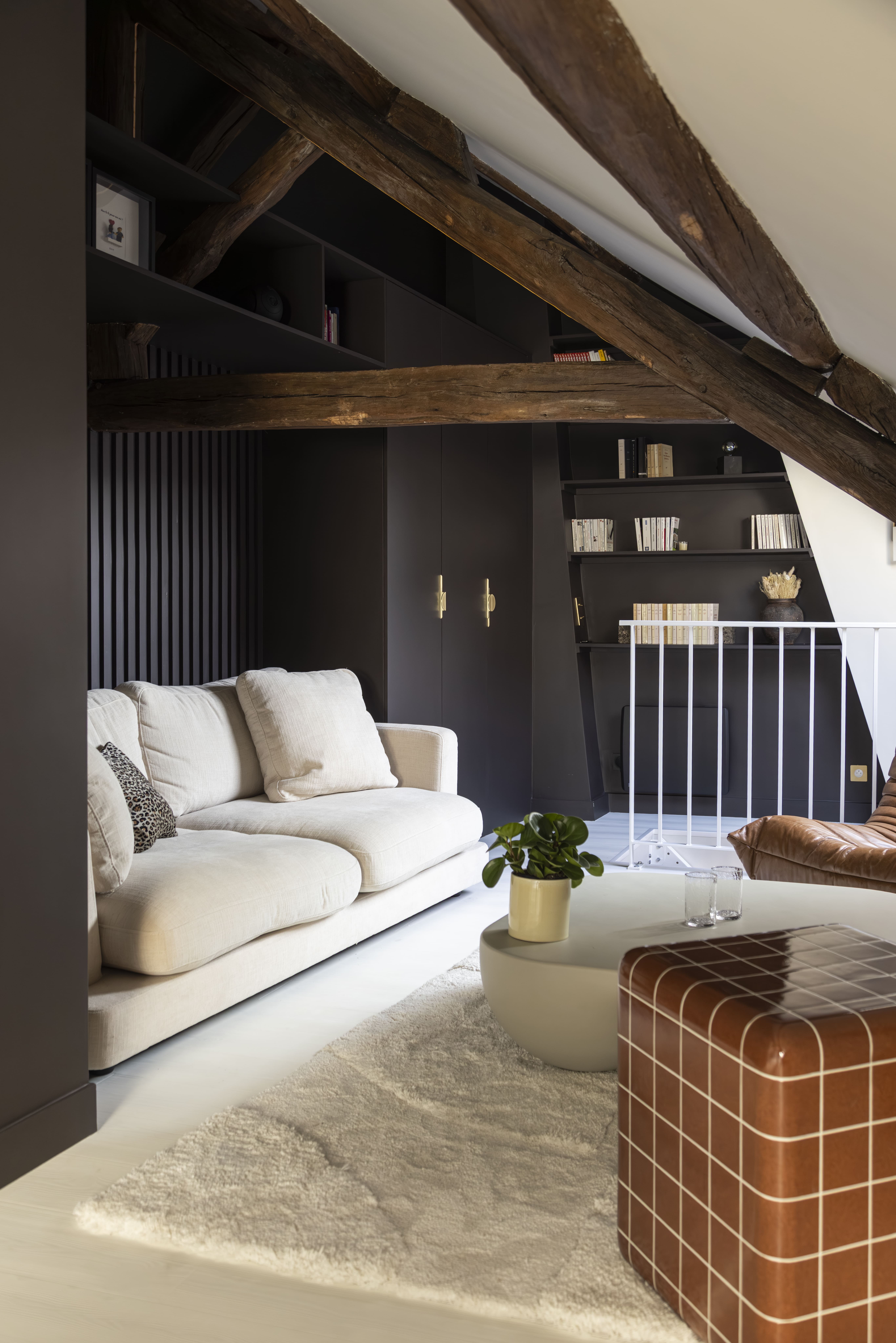 Salon sous combles avec poutres apparentes et décoration contemporaine – rénovation d’un duplex à Paris