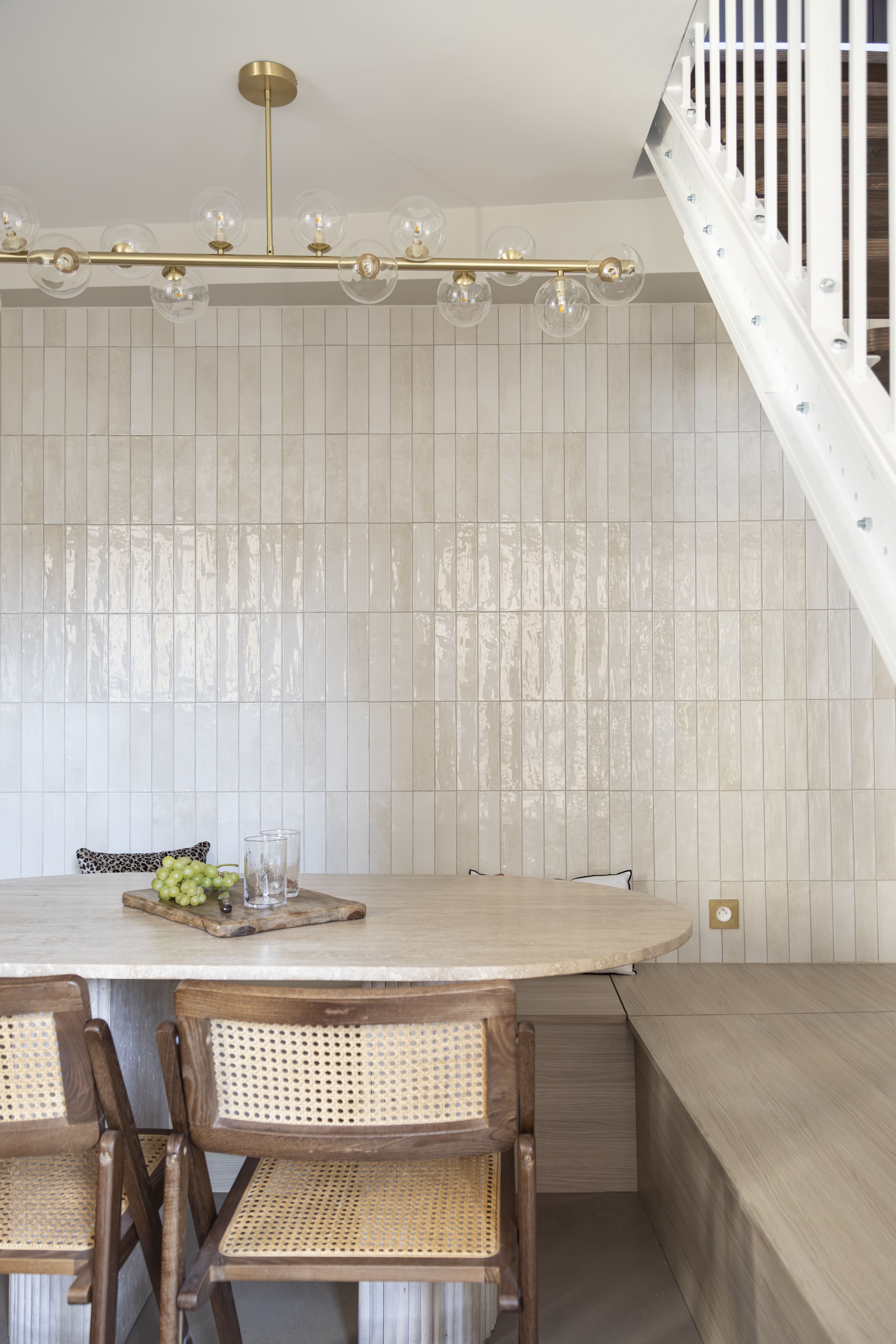 Salle à manger sous mezzanine avec mur en faïence blanche et touches dorées