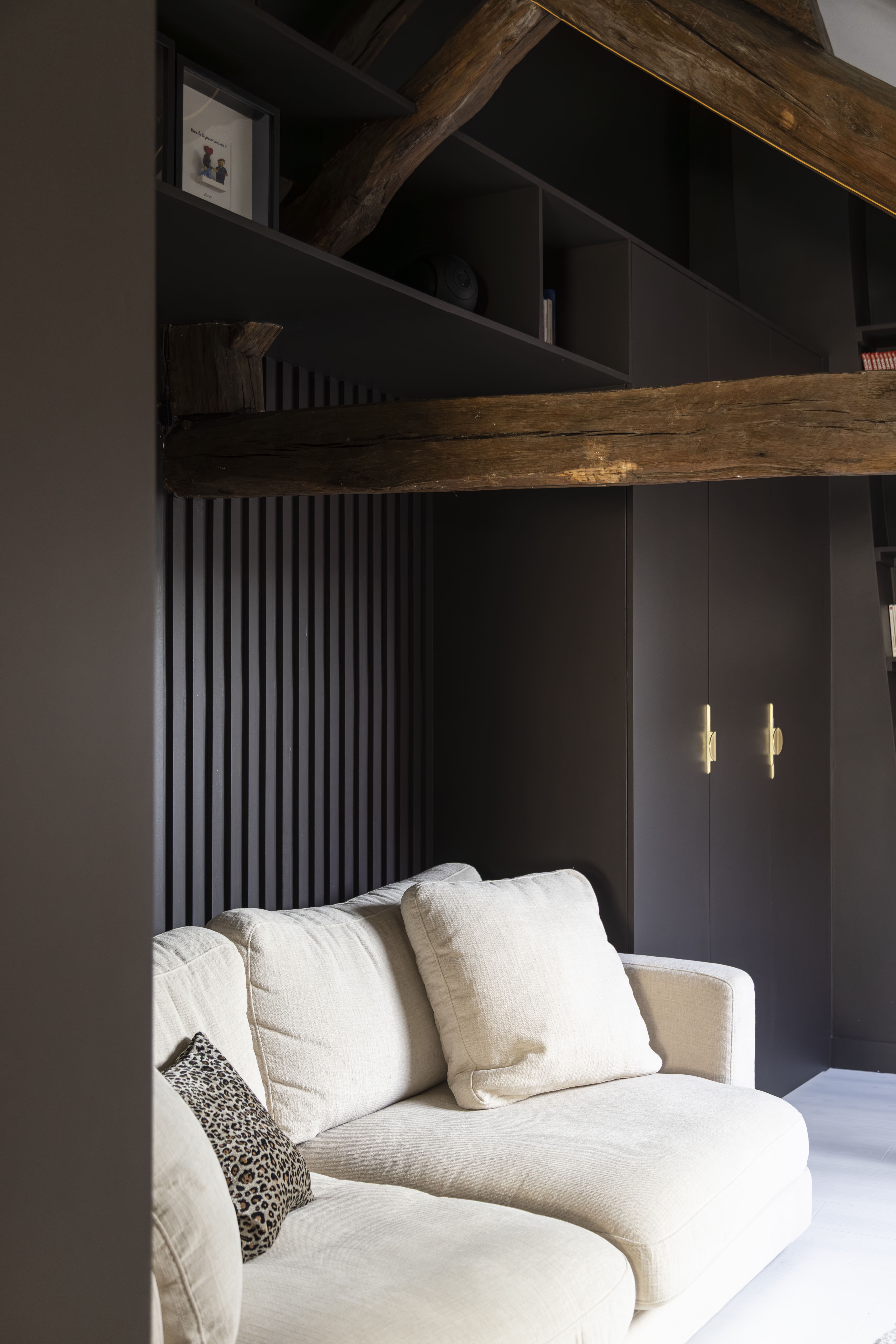 Salon design sous les toits avec poutres en bois et mur foncé – projet d’architecture intérieure à Paris