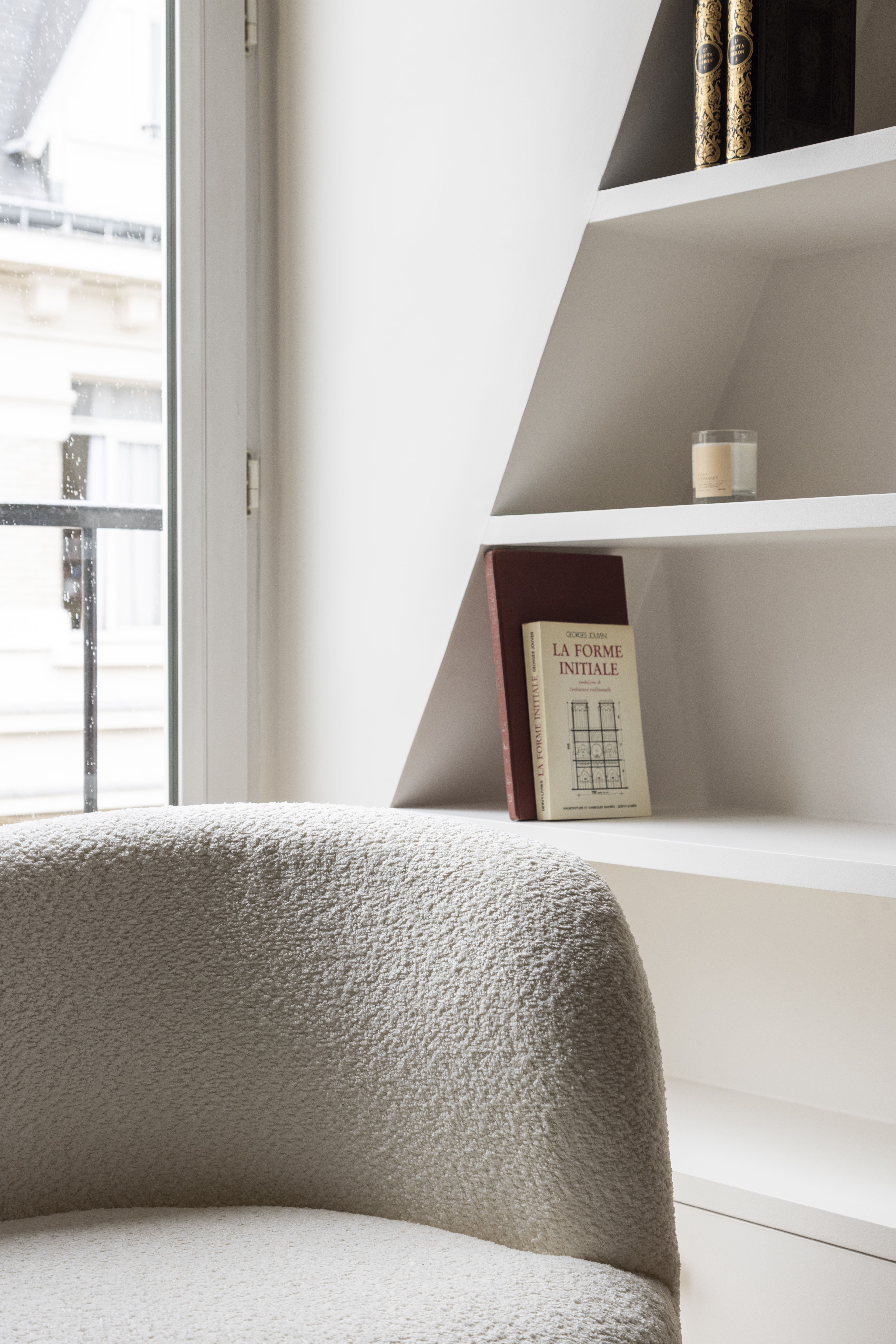 Détail de la bibliothèque sur mesure et fauteuil design près de la fenêtre