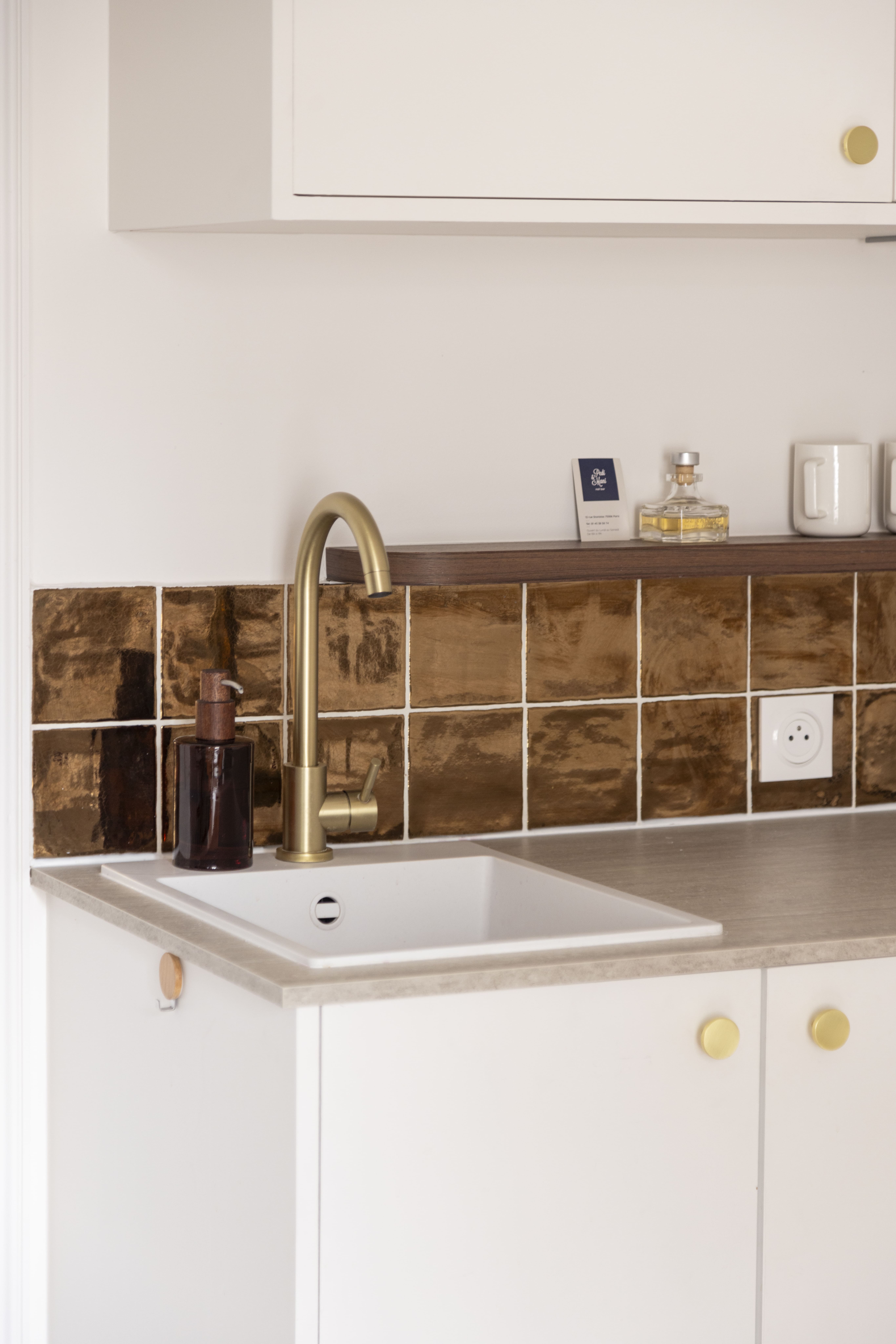 Cuisine rénovée à Paris avec crédence en carrelage doré et robinetterie en laiton