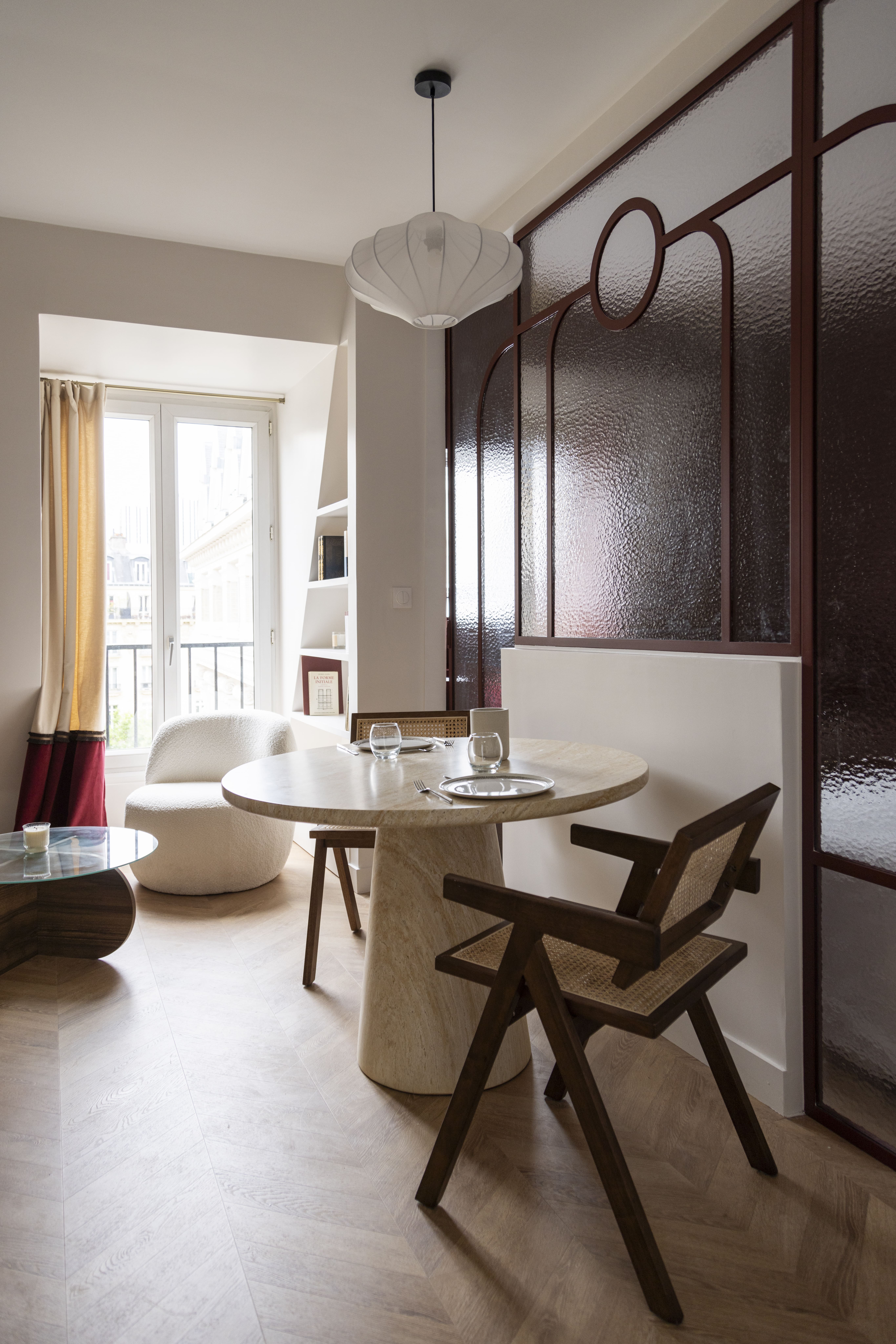 Vue d’ensemble d’un espace de vie lumineux avec table ronde et chaises en bois