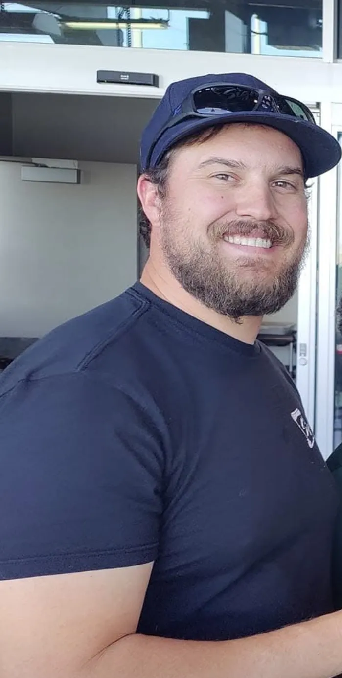 Smiling man in navy blue shirt and cap standing in an office