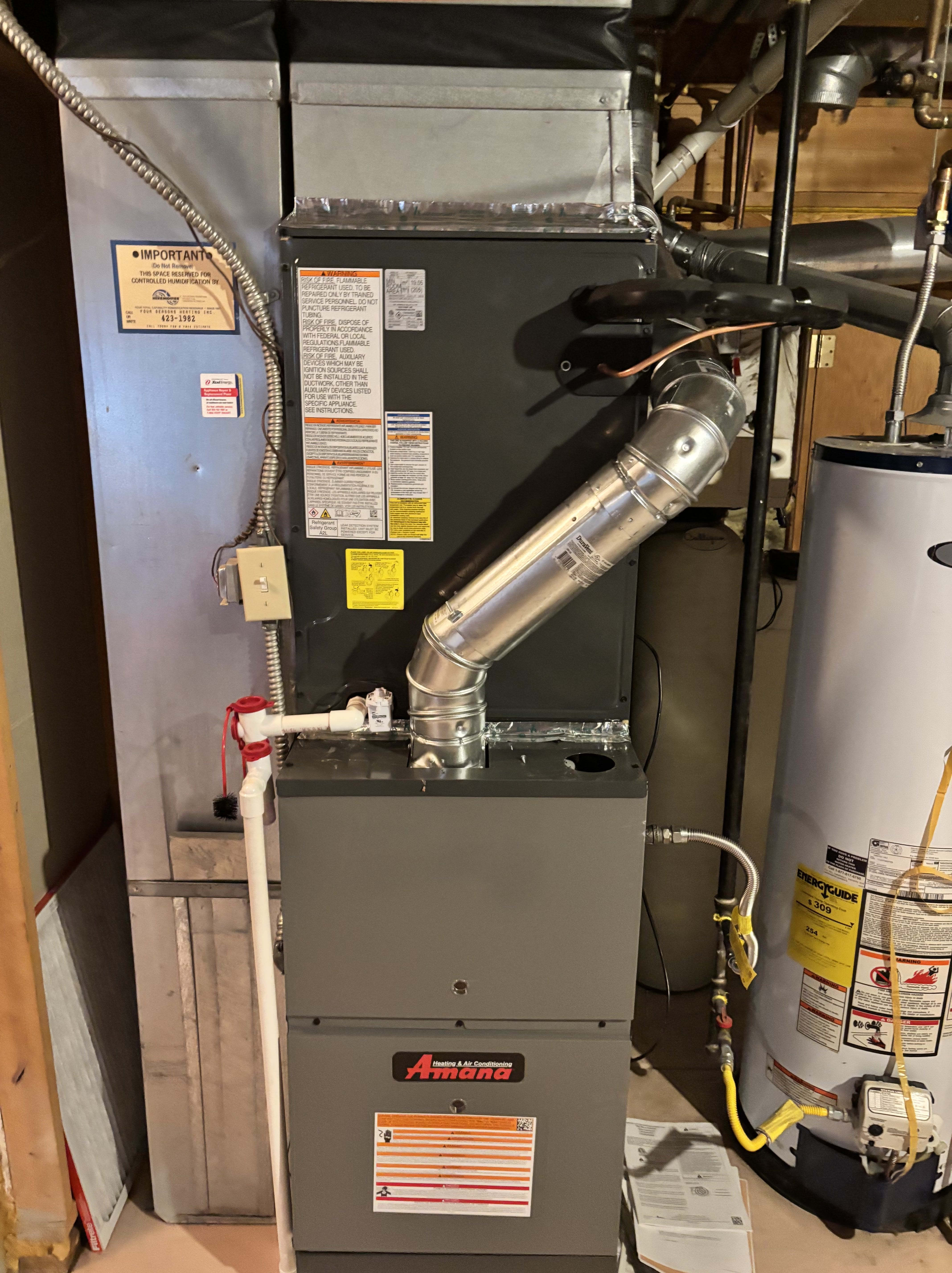 Amana furnace and water heater in a utility room with metal piping