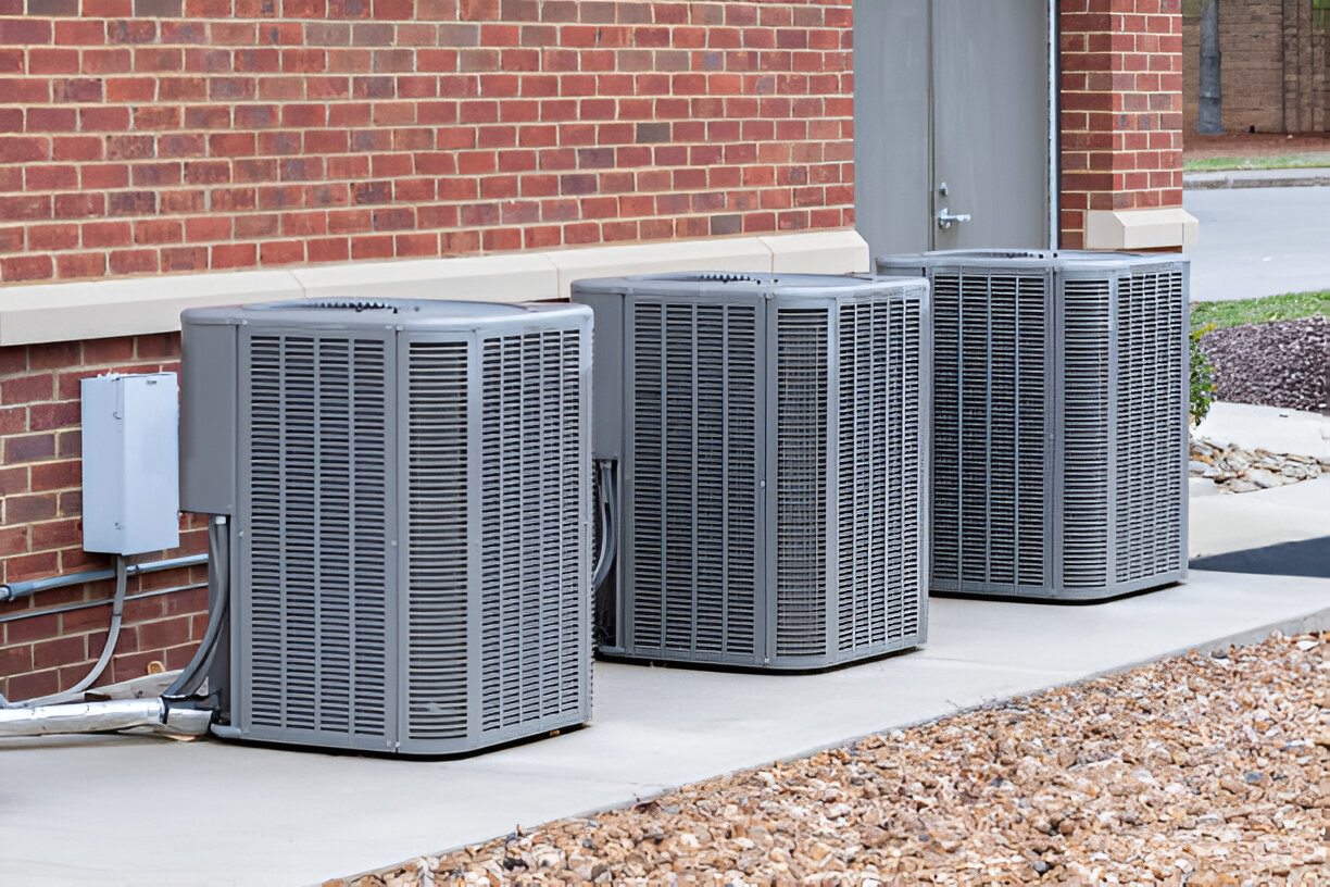 Multiple air conditioning units beside brick building on concrete pad