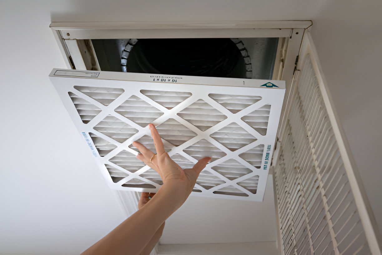Hand changing white air filter in home HVAC system
