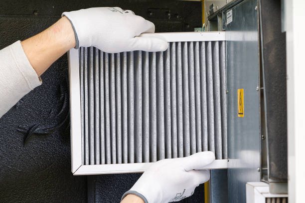 Hands in white gloves holding a clean air filter