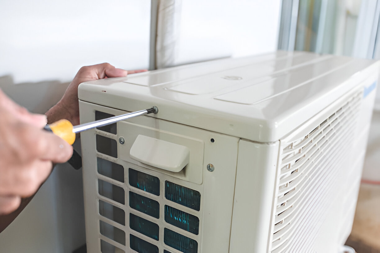 Technician repairing air conditioner with screwdriver